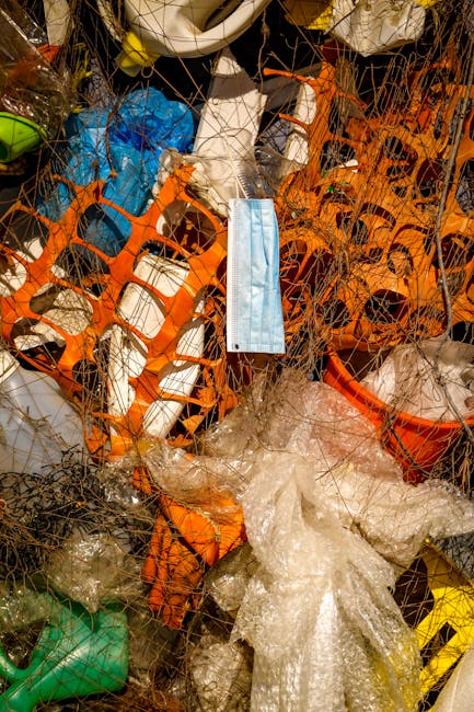 A large collection of mixed waste materials gathered around five overflowing bins on a paved street in front of a commercial building, which is under renovation or construction. The waste includes car